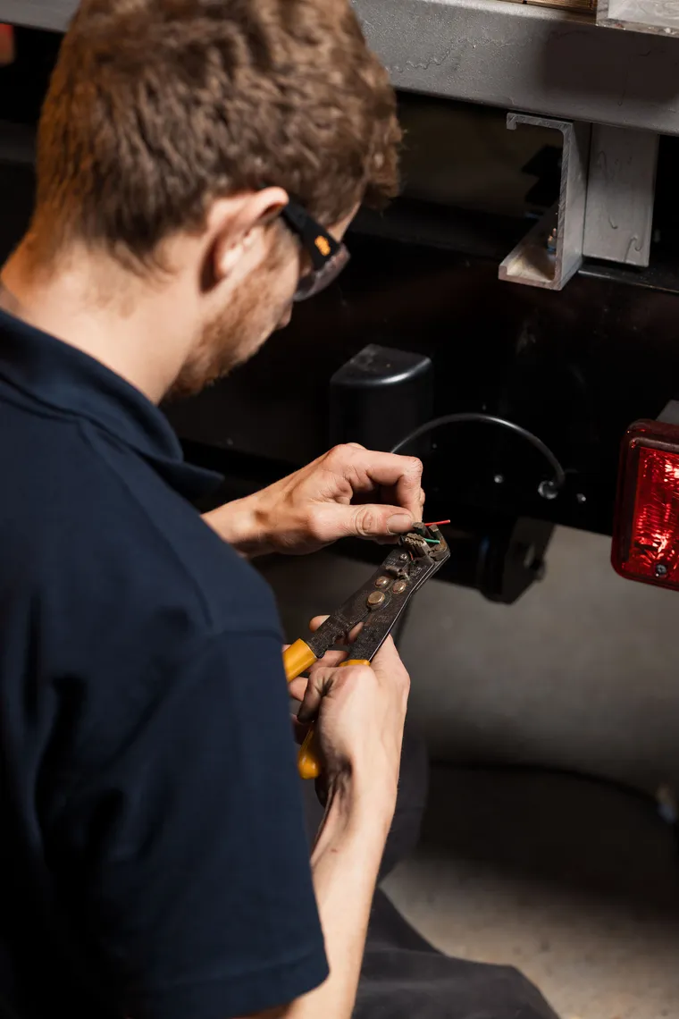 Technician preparing wiring on a commercial vehicle rear