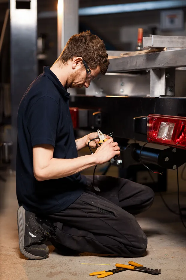 Technician wiring rear electrics on a new commercial body