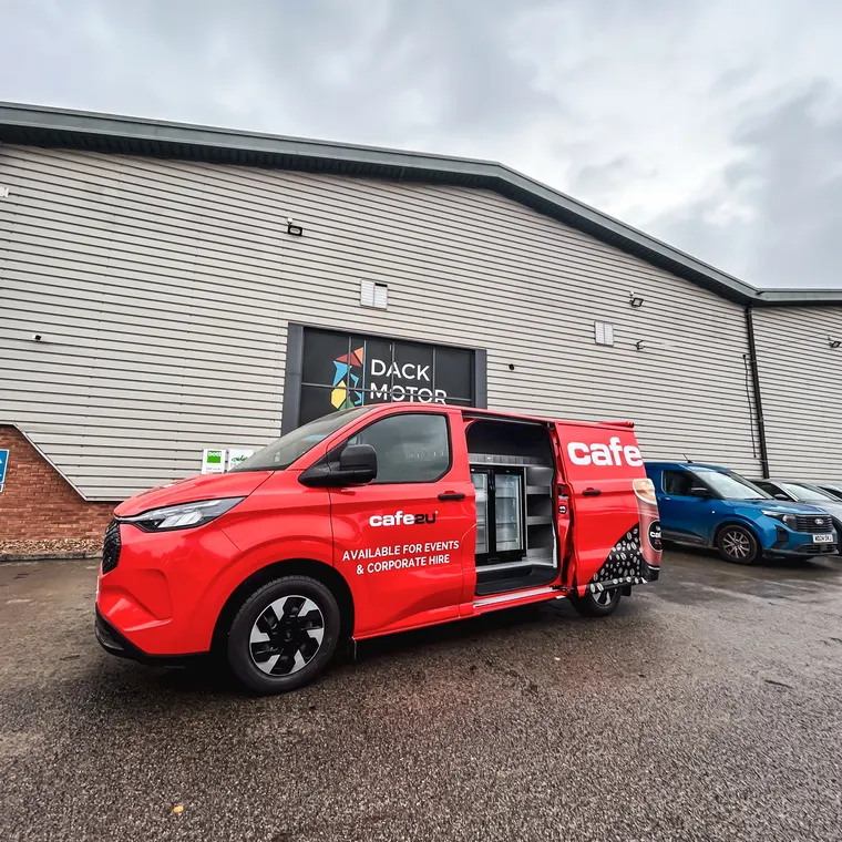 All-electric Cafe2U van with side door open outside the Dack Motor Group building